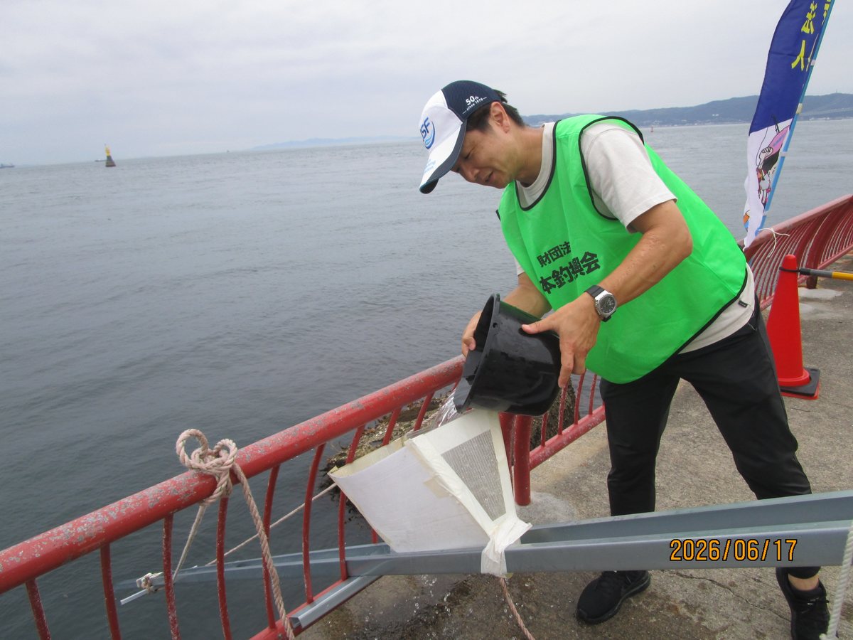 放流用の架台にバケツから稚魚を流す支部の役員