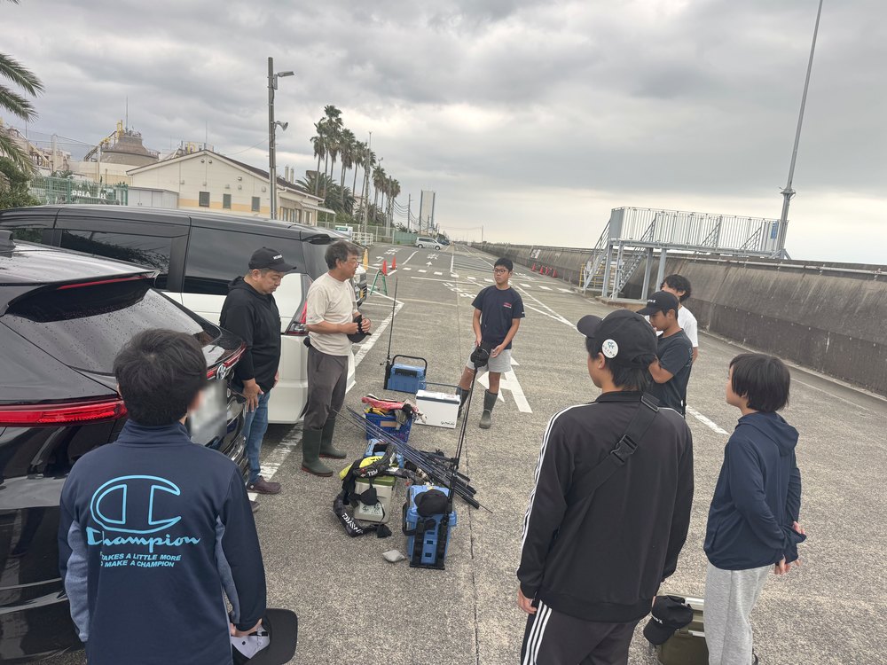 駐車場でナビゲーターの話を聞く部員