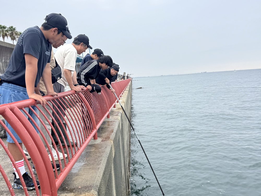 手すりから身を乗り出して海を見る部員