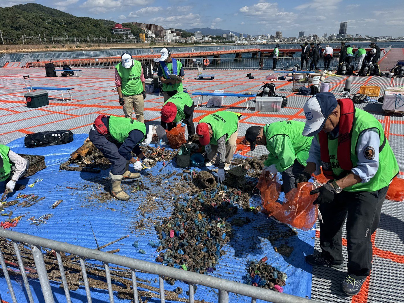 ブルーシートの上で引き上げたゴミを種類ごとに分ける参加者