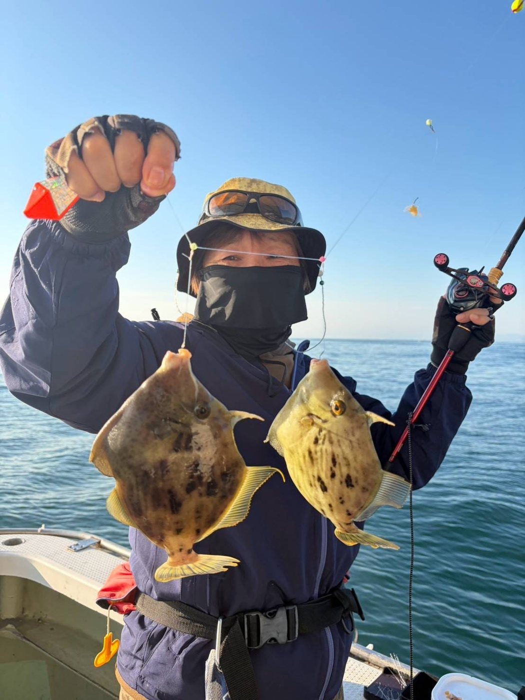 ダブルで釣り上げたカワハギを掲げる参加者